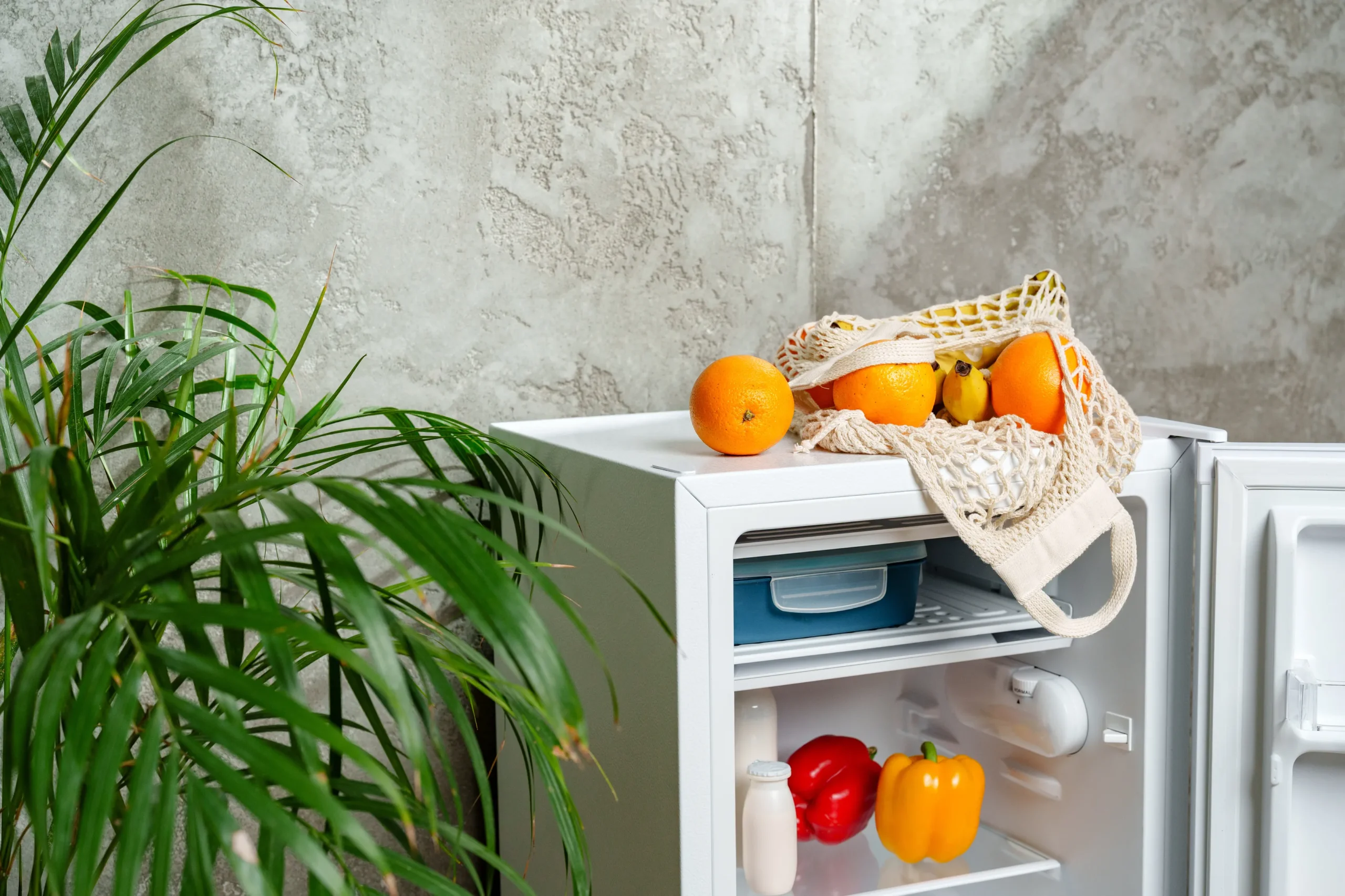 Fotografía de un minibar blanco de una suite de hotel con fruta fresca encima y la puerta abierta