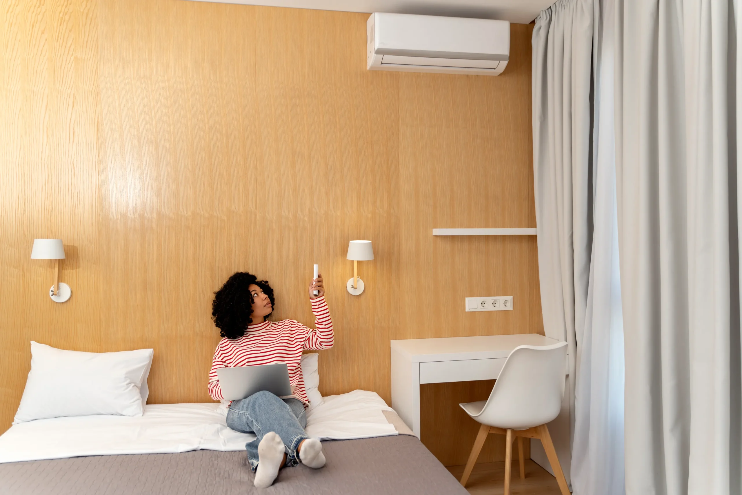 Imagen de una mujer controlando el clima de su minisplit en su cuarto de hotel