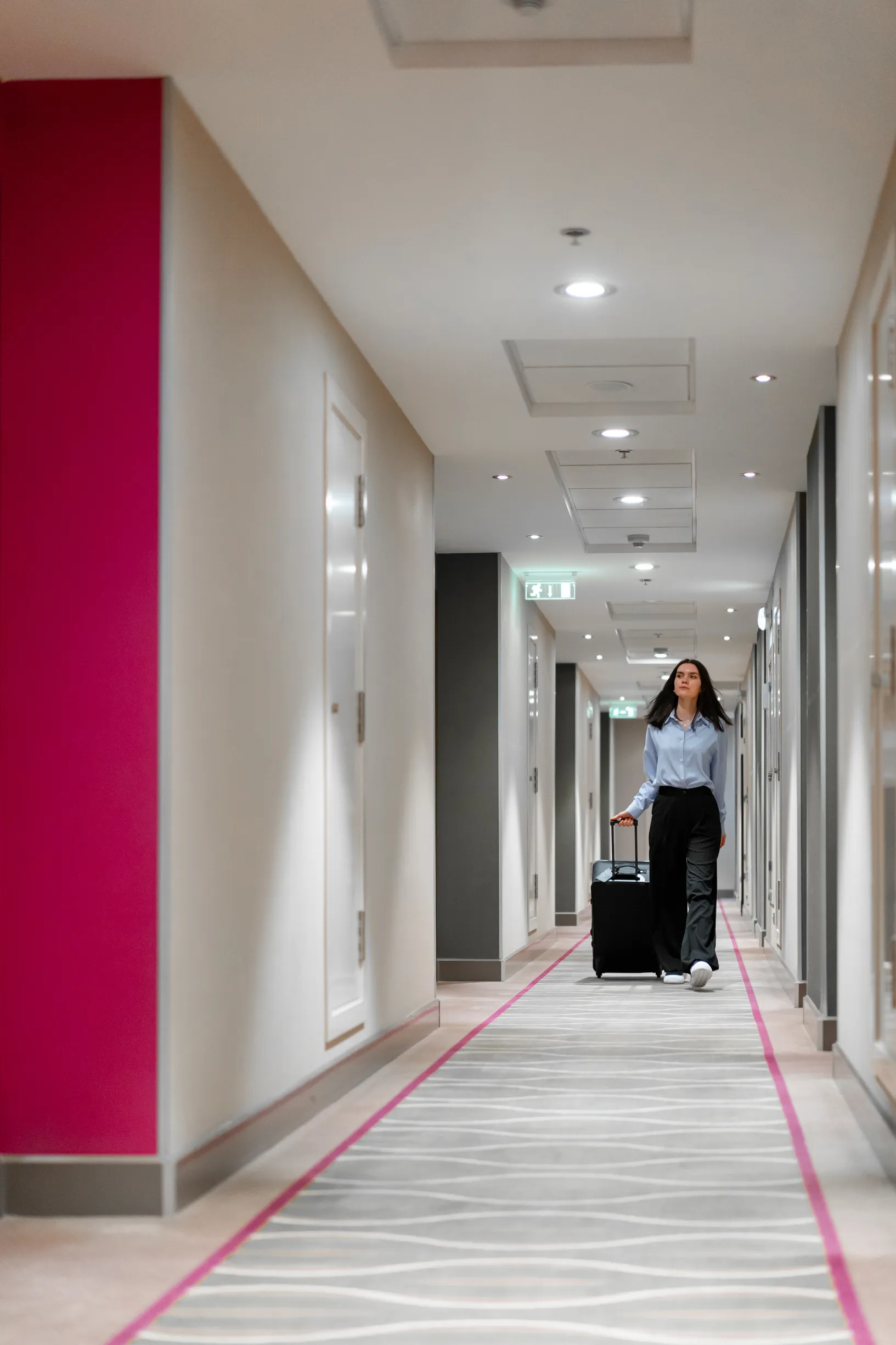 Foto de una mujer recorriendo pasillos de hotel modernos que cumple con las características de un hotel