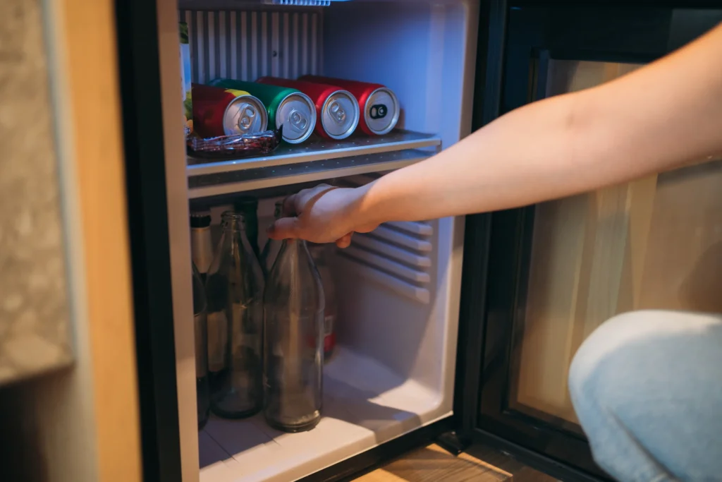 Fotografía del brazo de una Mujer sacando bebidas de su minibar para hoteles
