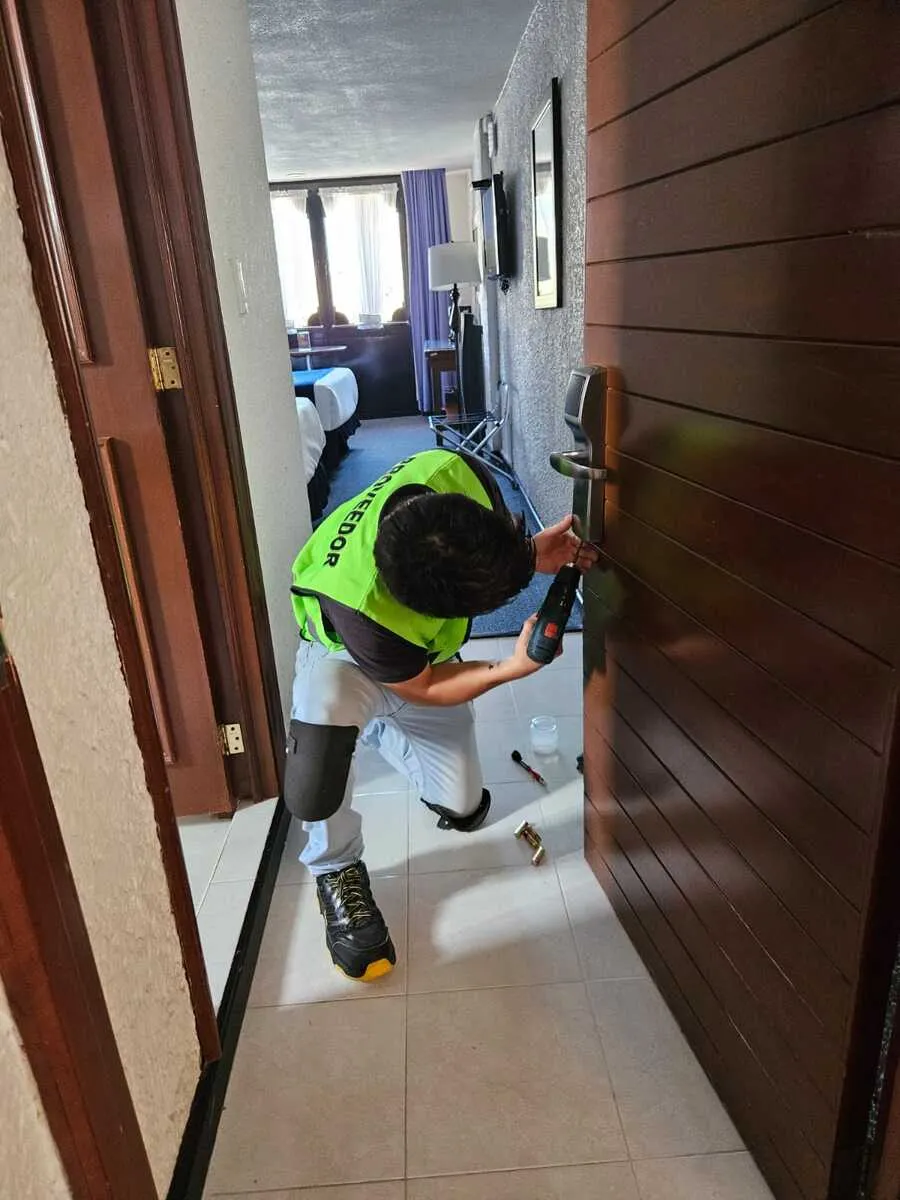 Foto a un especialista de Bama que sabe qué es una póliza de mantenimiento realizando servicio a la cerradura en un hotel